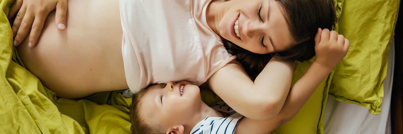 Pregnant Mother and Child laying down smiling