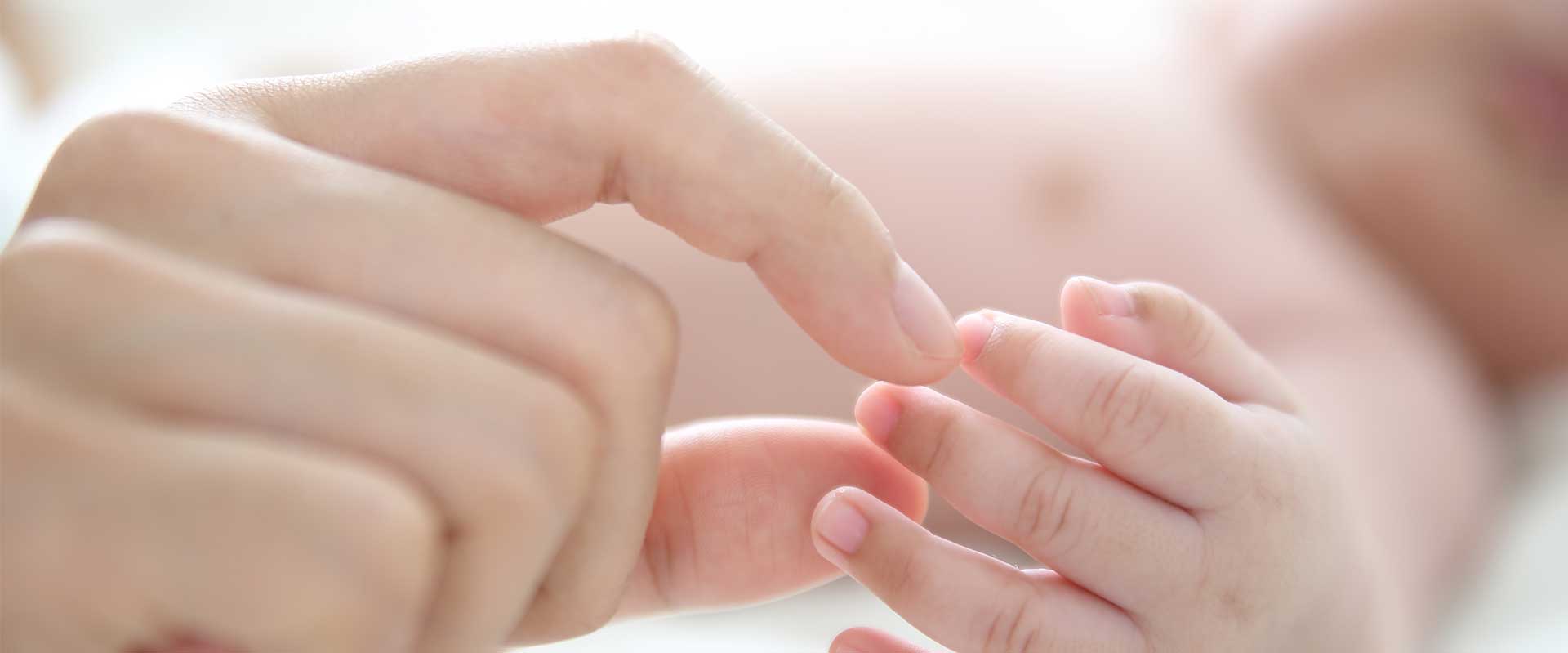 woman's hand touching baby's hand